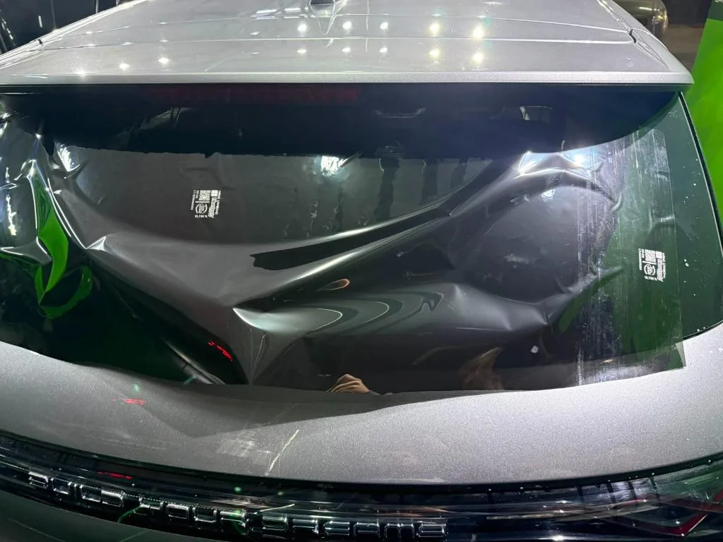 Instalador aplicando película antivandalismo premium nos vidros traseiros do carro